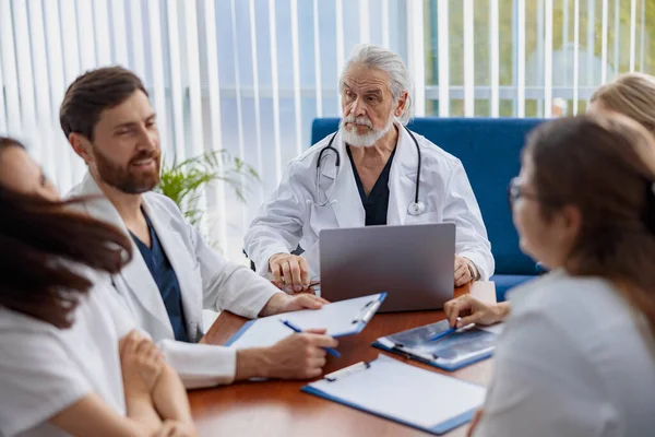 Group of doctors sitting at meeting table in conference room during seminar. High quality photo