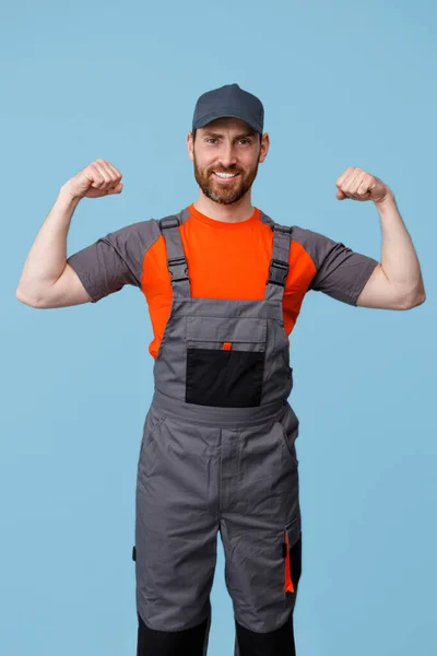 Hombre Constructor Positivo Uniforme Mostrando Sus Bíceps Cámara Sonrisa Fondo — Foto de Stock