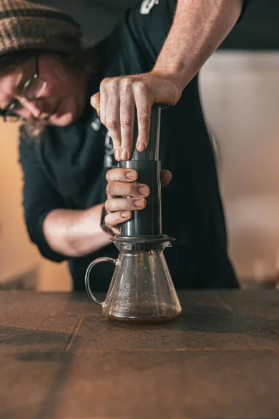 Barista press to device and coffee drops pours trought aeropress to pot. Coffee brewing method