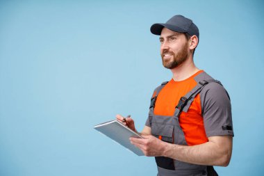 Üniformalı gülümseyen erkek kurye tableti tutuyor ve iş notları alıyor. Boşluğu kopyala