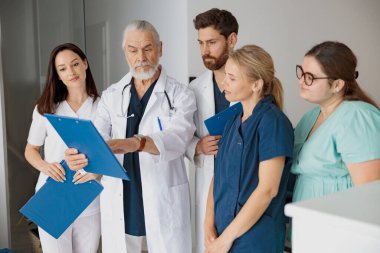Hastanedeki stajyerlere hasta teşhisini tartışan profesyonel bir doktor.