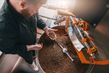Erkek barista elleri taze kavrulmuş kahve çekirdeklerini satışa sunar.