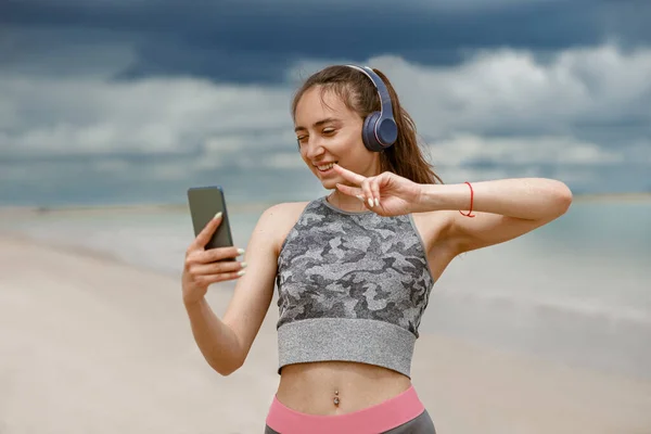 Uśmiechnięta Sportowa Kobieta Słuchawkach Robiąca Selfie Tle Oceanu Wysokiej Jakości — Zdjęcie stockowe