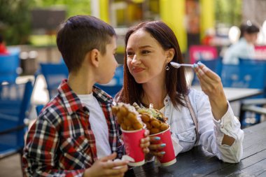 Güzel, genç bir anne ve yaz günü şehirde waffle yiyen tatlı bir oğul. Hafta sonu. Açık hava..