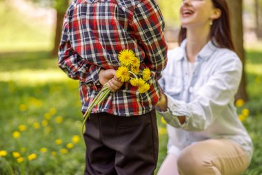 Anneye vermeden önce karahindibaları küçük çocuğun sırtında kapat. Annem için çiçekler. Burada.