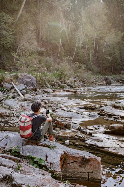 Rear Man Tourist Backpack Sitting Rock River Taking Photo Smartphone — 图库照片