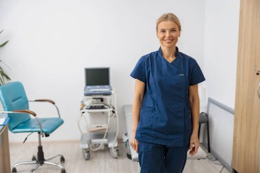 Gülümseyen doktor portresi, ultrason uzmanı klinikteki iş yerindeki kameraya bakıyor.