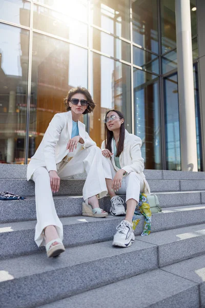 İki bayan arkadaş şehir manzarasının arka planında dinleniyor.