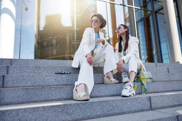 Moda kıyafetleri içinde gülümseyen bayan arkadaşlar şehirde dinleniyor. Bulanık arkaplan