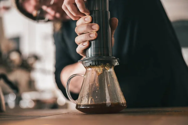 Barista press to device and coffee drops pours trought aeropress to pot. Coffee brewing method