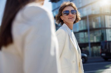 Moda kıyafetleri içindeki kadınlar iş merkezinin yakınında yürürler. Bulanık arkaplan