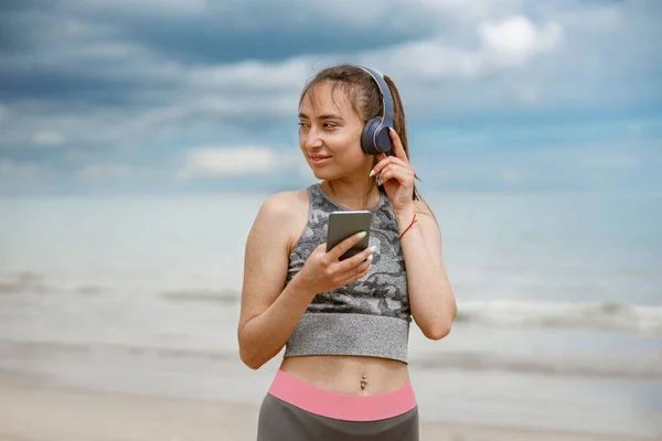 Młoda Kobieta Odzieży Sportowej Słucha Muzyki Słuchawkach Przy Plaży Tle — Zdjęcie stockowe