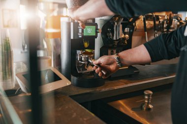 Barista kahve makinesini kullanarak portafilterin içine kahve çekirdeklerini öğütüyor. Yüksek kalite fotoğraf