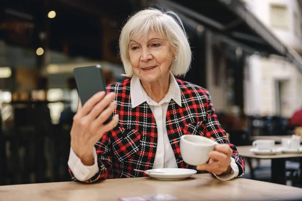 Happy Healthy Aged Woman Browsing Mobile Phone While Drinking Her — Stok Foto