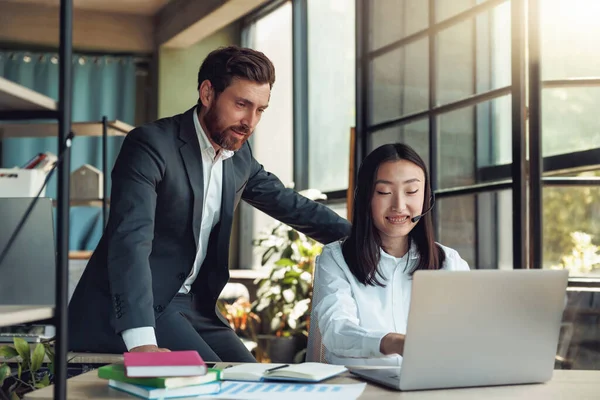 Two people working in a modern office and discussing a new project. Blurred background