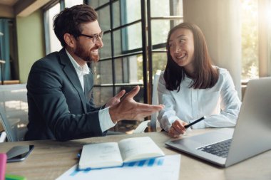 Two people working in a modern office and discussing a new project. Blurred background
