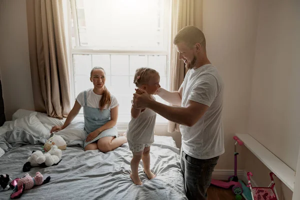 Happy young parent playing with his baby girl spending time together lie on bed. Blurred background