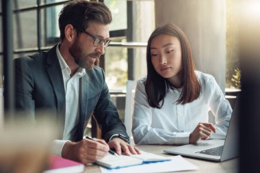 Two people working in a modern office and discussing a new project. Blurred background