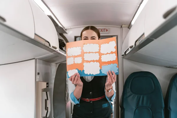 Smiling Female Flight Attendant Holding Instruction Booklet Standing Board — Foto de Stock