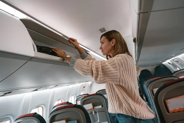 Wanita Pelancong Menempatkan Bagasi Loker Overhead Pesawat Selama Naik Foto — Stok Foto