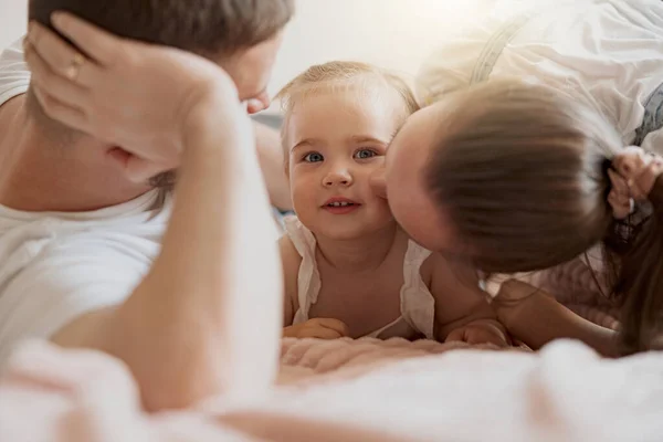 Happy young parent playing with his baby girl spending time together lie on bed. Blurred background