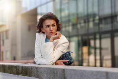 Focused woman in white suit standing near business centre and looking away