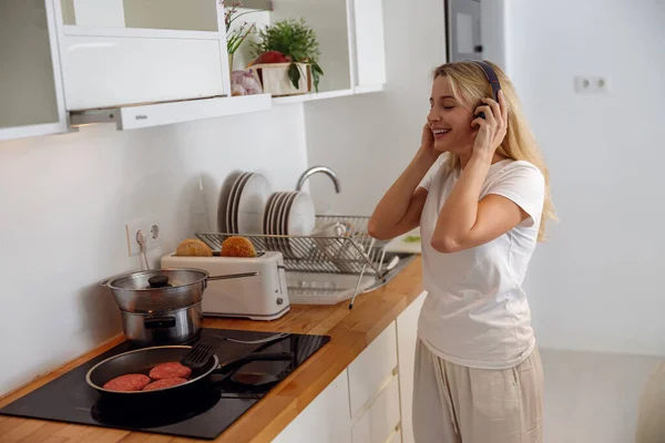 Blonde Attractive Female Headphones Listening Music Cooking Kitchen Making Breakfast — Stok fotoğraf