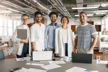 Happy group of businesspeople laughing cheerfully in a modern workplace. Blurred background
