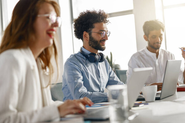 Различные сотрудники анализируют отчеты о продажах, работая вместе в офисе. Размытый фон