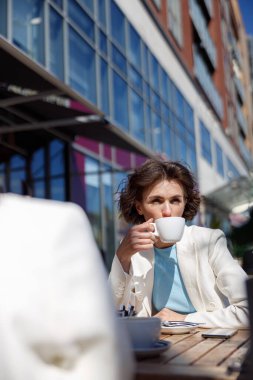 Two attractive female friends drinking coffee sitting in cafe. Blurred background