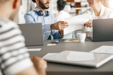 Diverse coworkers analyzing sales report while working together in office. Blurred background