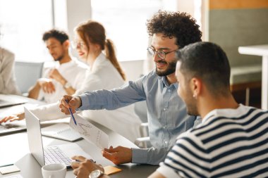 Happy group of businesspeople laughing cheerfully in a modern workplace. Blurred background