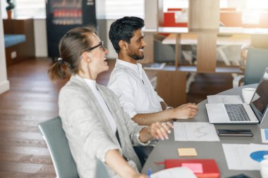 Two coworkers working together analyzing the charts in office. Blurred background
