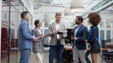 Group of colleagues talking standing in office indoors smiling during break. High quality 4k footage
