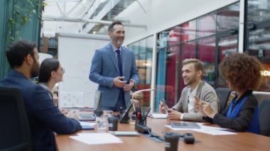Mature coach or speaker make flip chart presentation to diverse businesspeople at meeting