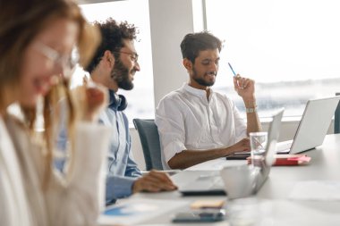 Diverse coworkers analyzing sales report while working together in office. Blurred background