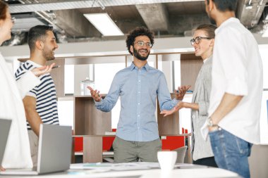 Happy group of businesspeople laughing cheerfully in a modern workplace. Blurred background