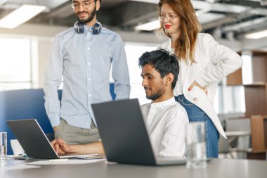 Diverse coworkers analyzing sales report while working together in office. Blurred background