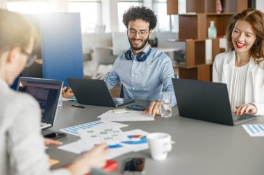 Diverse coworkers analyzing sales report while working together in office. Blurred background