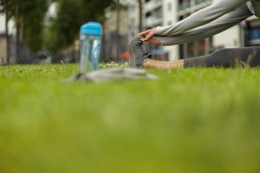 Şehir parkında yeşil çimenler üzerinde esneme egzersizi yapan bir kadın. Yüksek kalite fotoğraf