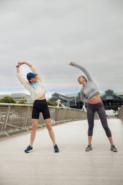 Şehirdeki yaya köprüsünde esneme egzersizi yapan güzel spor kadınları. Sağlıklı yaşam tarzı