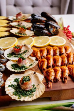 Kabuklu lezzetli kızarmış midyeler krema soslu ve kabuklu istiridye, pastırma ve otlu ve ahşap kesim tahtasında dilimlenmiş sarı sulu limon.