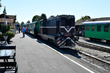 Stainz, Avusturya - 23 Eylül 2021 Sözde Flascherlzug 'un renkli vagonları - şişe treni - dar bir demiryolu ve batı Styria' da popüler bir turistik eğlence merkezi, tren istasyonunda kimliği belirsiz insanlar