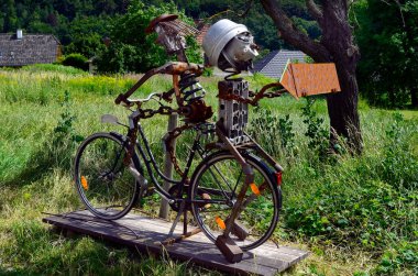Austria, funny character built from spare parts sitting on bicycle with direction sign in the Unesco World Heritage site in Danube valley