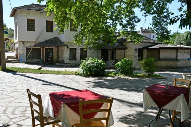 Ioannina, Yunanistan - 27 Haziran 2021: Pamvotis Gölü 'ndeki küçük bir adadaki bir restoranın dış bölgesinde bilinmeyen turist, sandalye ve masalar