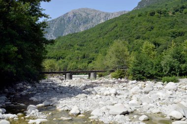 Yunanistan, nehir yatağında kaya ve taşlar ve Tzoumerka- Peristeri- Arachthos Boğazı ve Acheloos Vadisi 'ndeki Arachtos Nehri' nin bir kolunun üzerinde tek şeritli bir köprü.