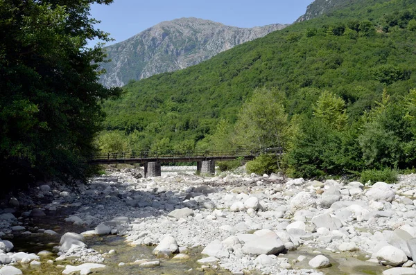 Yunanistan, nehir yatağında kaya ve taşlar ve Tzoumerka- Peristeri- Arachthos Boğazı ve Acheloos Vadisi 'ndeki Arachtos Nehri' nin bir kolunun üzerinde tek şeritli bir köprü.