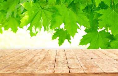 Modelleme. Yaprak bokeh arkaplanlı boş ahşap güverte masası.