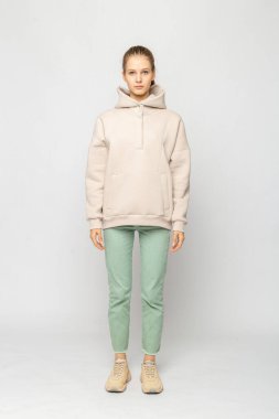 Yeşil kargo pantolonlu ve bej kapüşonlu kız beyaz üzerinde izole edilmiş.