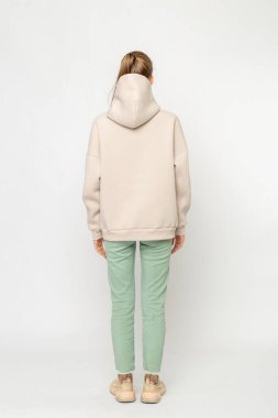 Yeşil kargo pantolonlu ve bej kapüşonlu kız beyaz üzerinde izole edilmiş.